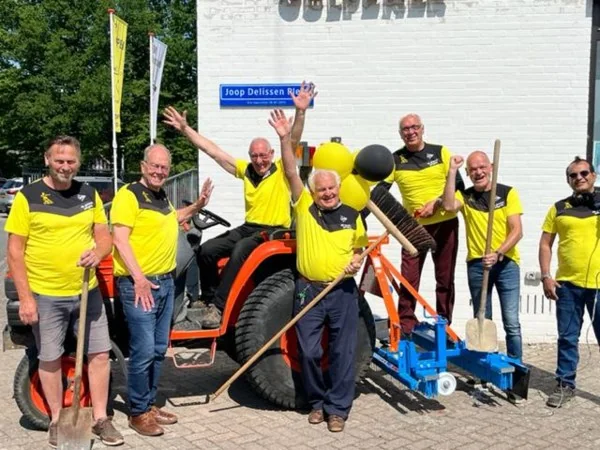 De Groene Jongens van FC Gulpen poseren trots voor het clubgebouw bij het Joop Delissen Plein, gekleed in geel-zwarte shirts met onderhoudsmaterialen